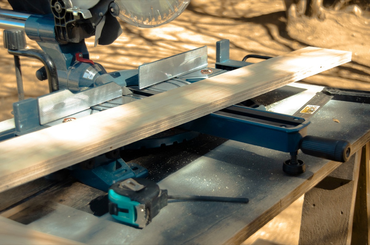Scie à onglet découpant une planche de bois dans l'atelier