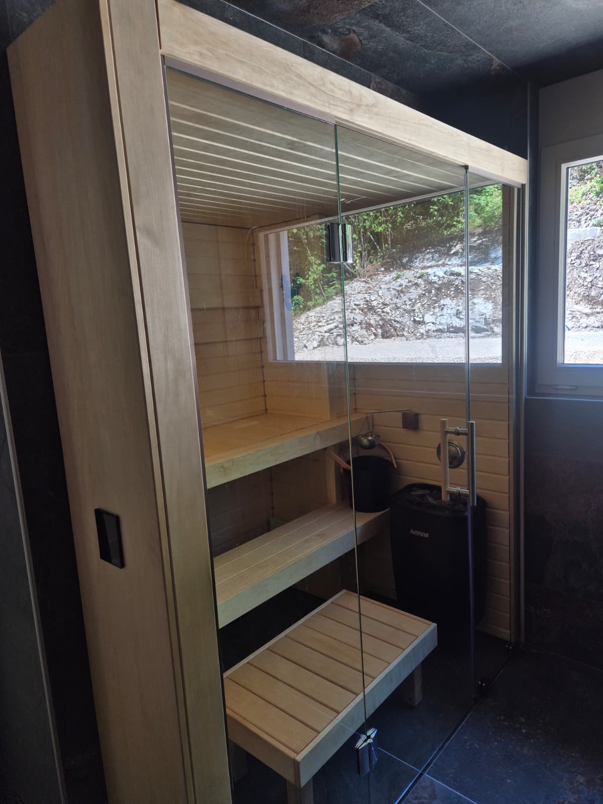 Sauna vitré avec vue sur un paysage rocheux, lumière du jour